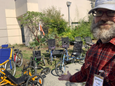 A guy with a beard and hat standing in front of a large variety of adaptive cycles. A guy with a beard and hat standing in front of a large variety of adaptive cycles.